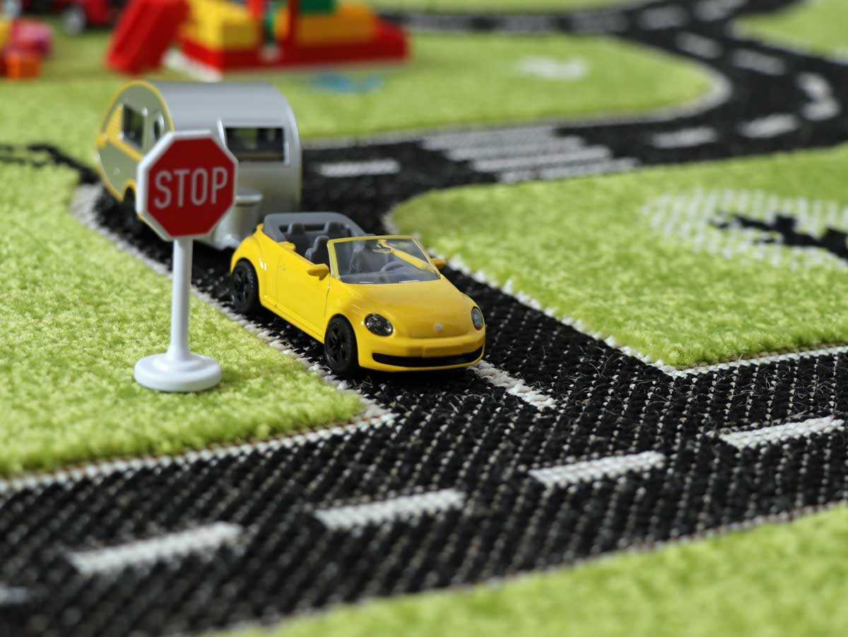 Detailaufnahme einer Straßenkreuzung mit einem Käfer Cabrio mit Wohnanhänger