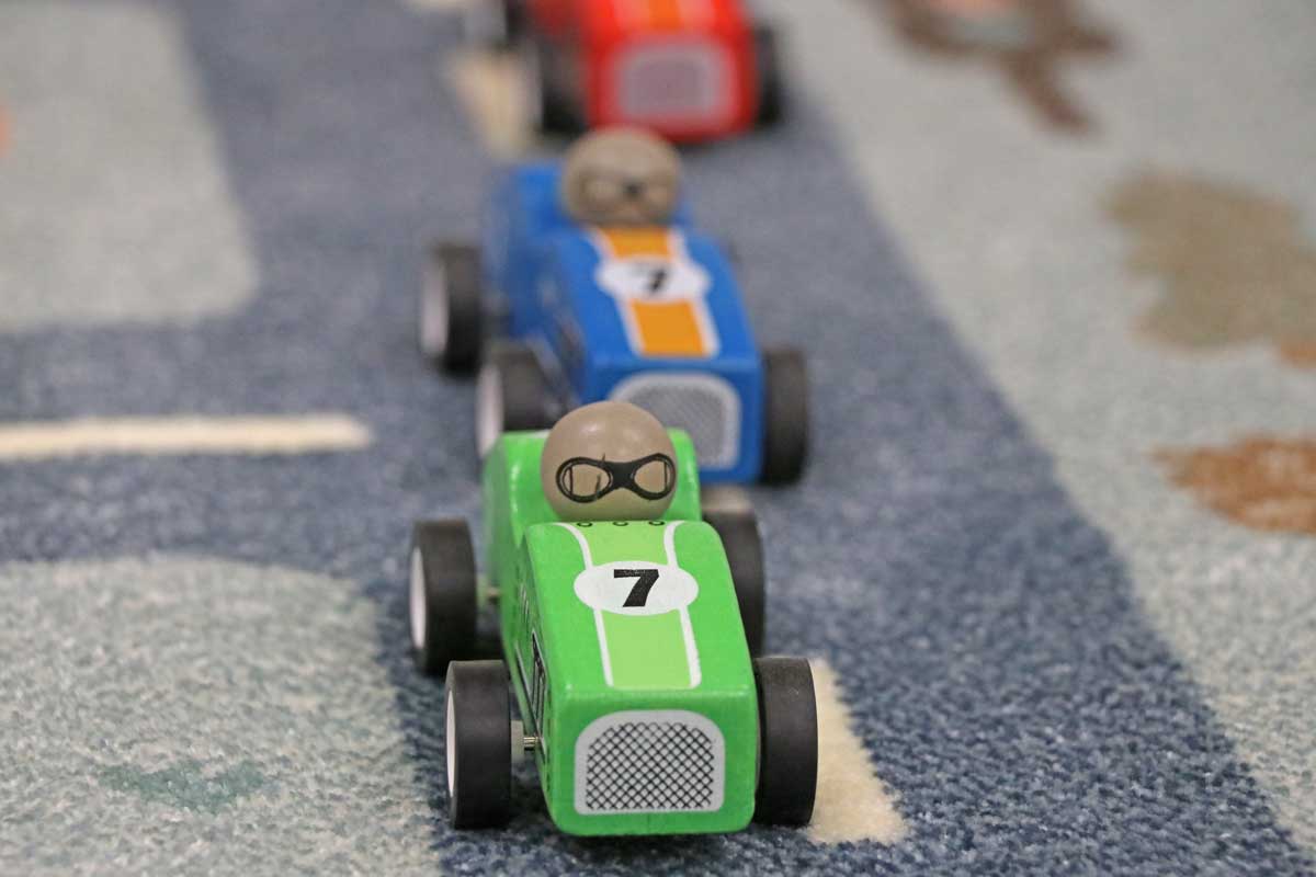 Detailaufnahme eines Rennwagens, der im Rennen gegen drei andere Autos auf dem Teppich in Führung liegt.